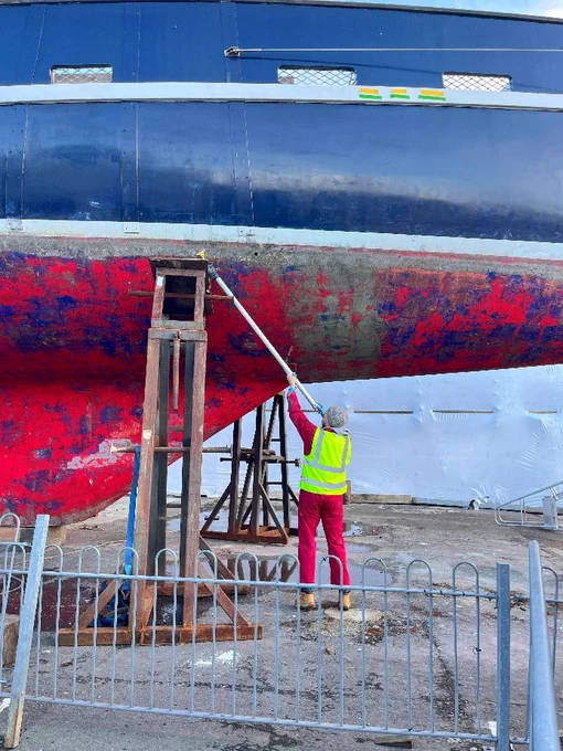 Cleaning the hull with a long-handled scraper!