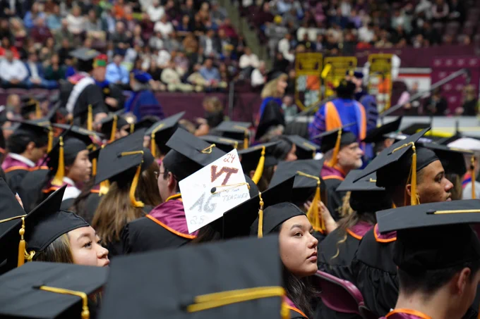 A graduation cap with VT AG Teacher on the top is visible among unadorned black caps