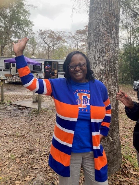 Doctor Alma Littles in an orange and blue Florida Gators sweater and T-shirt in the woods.