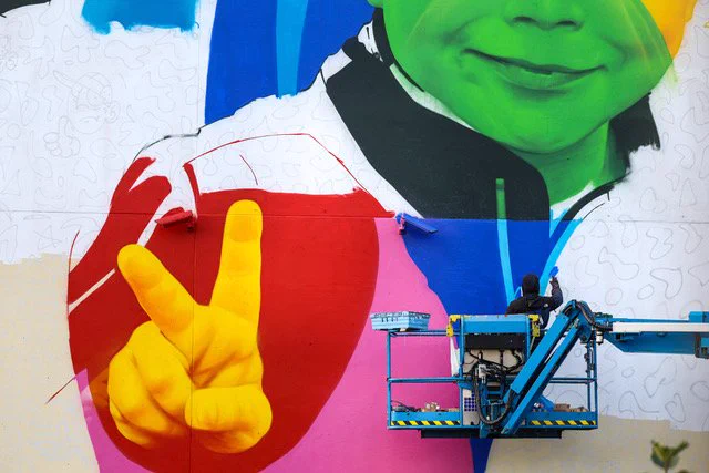 Aches at work on a large scale mural on the side of the Holiday Inn, Linen Quarter, Belfast