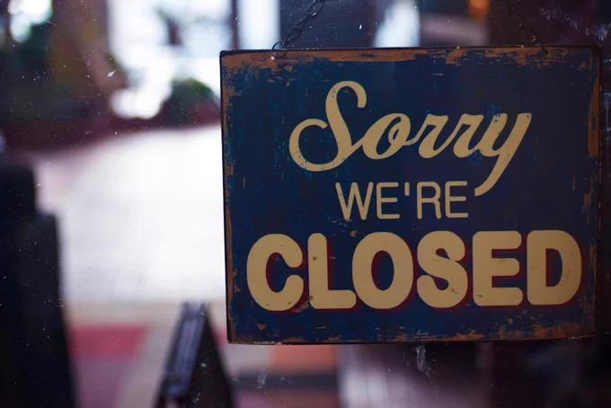 A rustic 'Sorry We're Closed' sign displayed on a shop door, atmospheric lighting.