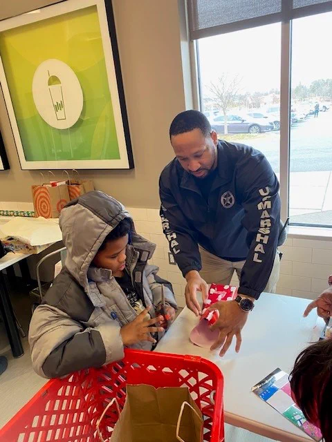 A Deputy U.S. Marshal helps a child wrap a gift for the upcoming holidays. 