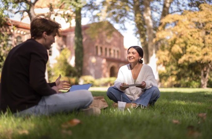 Two Chico State students study together while sitting on Kendall Lawn.
