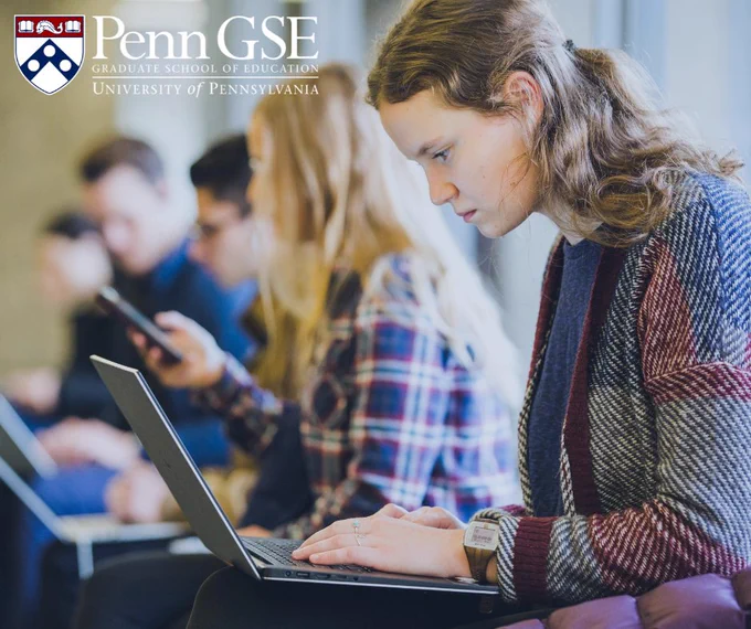 Students using laptops and mobile devices in a hall at the University of Pennsylvania's Graduate School of Education.