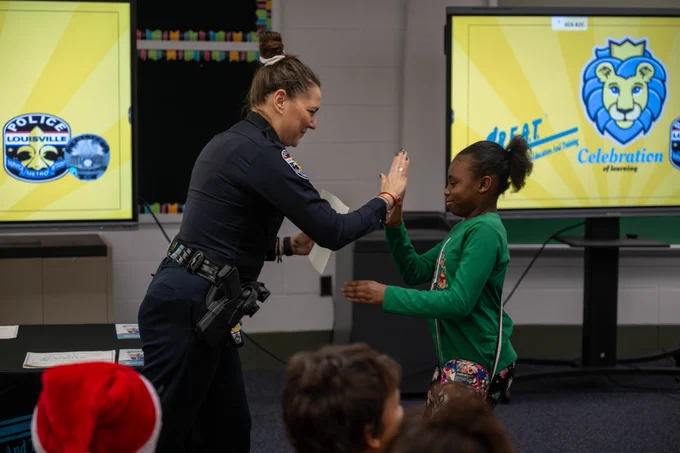 A police officer and a student do a high-five.
