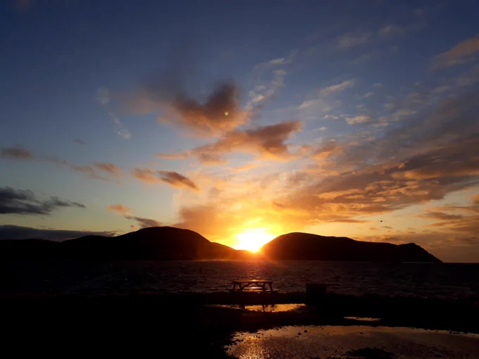 The sun setting in the space between the hills of Ward Hill and Cuilags on the island of Hoy in Orkney
