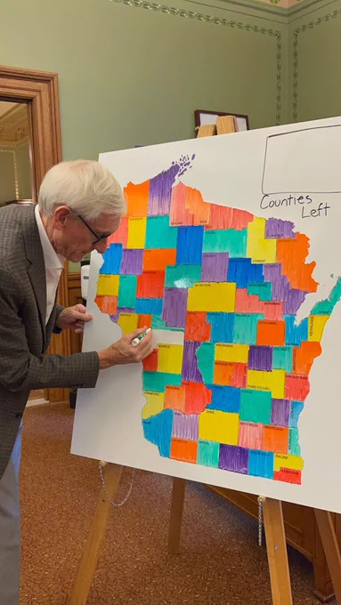 Gov. Evers colors in a map of Wisconsin.