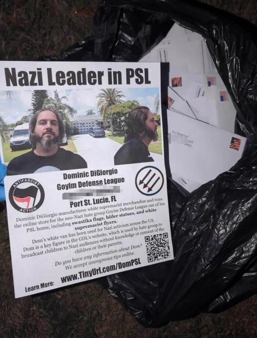 A flyer that says 

"Nazi Leader in PSL

Dominic DiGiorgio
Goyim Defense League
Port St. Lucie, FL"

The flyer has a photo of dominic digiorgio in front of a picture of his home. The flyer is on top of a garbage bag of envelopes.