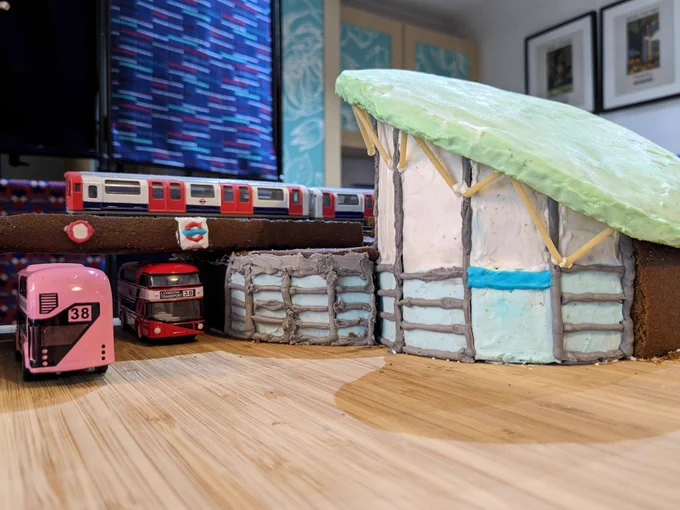 A gingerbread Hounslow East station with model busses and a train.