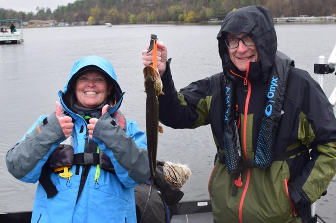 Gov. Evers holds up his northern pike out on a boat. 