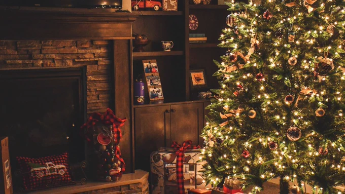 Christmas tree with white lights, gold ornaments, and a fireplace