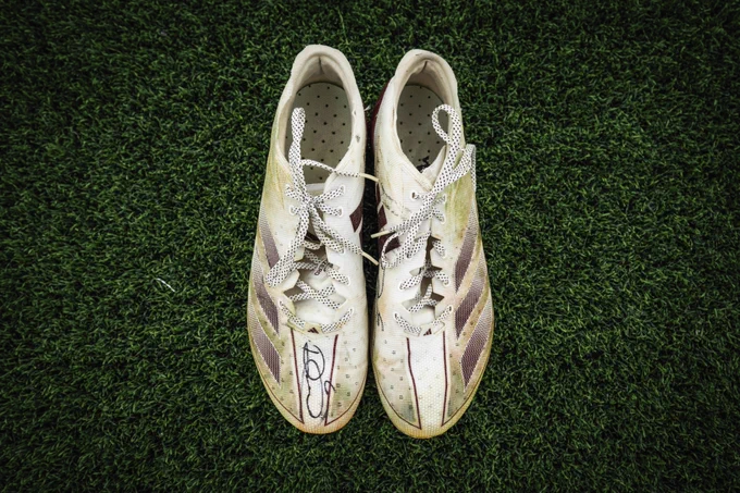 Photo of signed Dante Fowler Jr. cleats sitting on turf. 
