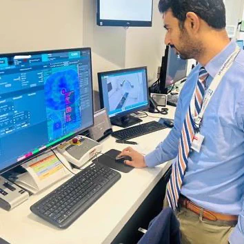 Dr. Desai in a blue dress shirt and tie observing a computer screen with imaging.