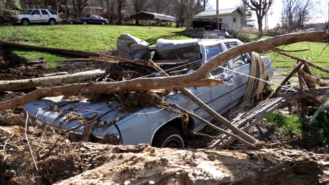 A damaged vehicle pinned under a tree in Avery County due to Hurricane Helene.