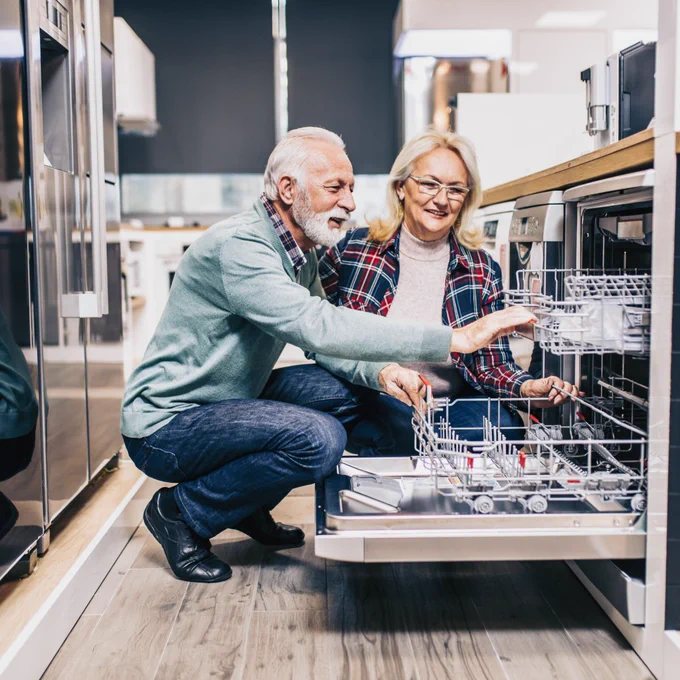 Older couple looking at an open dishwasher in an appliance store