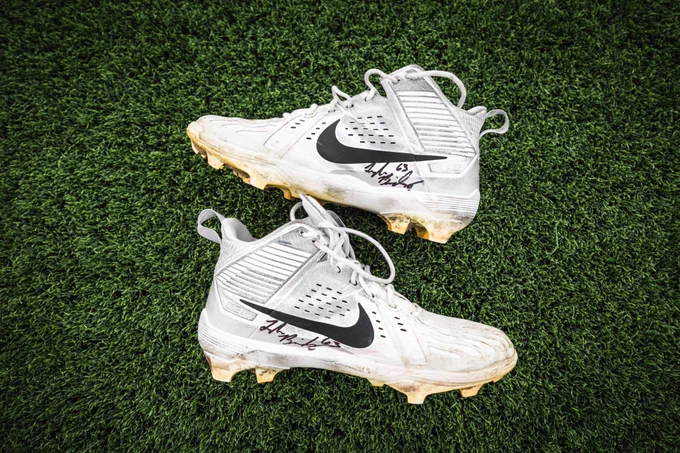 Photo of signed Tyler Biadasz cleats sitting on turf. 
