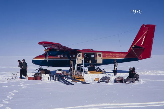 Des personnes déchargent des fournitures d’un avion posé sur un terrain enneigé et les placent sur des motoneiges et des traîneaux. Texte sur l’image : 1970