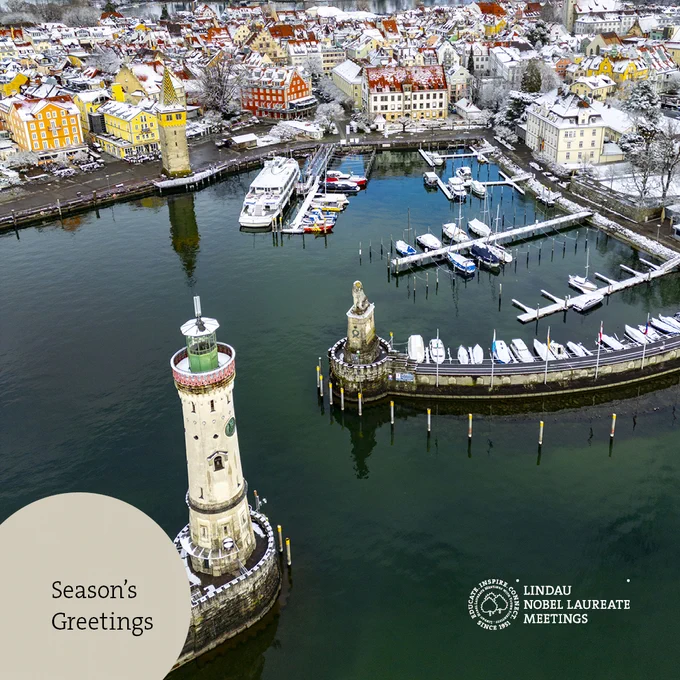 Snowy Lindau harbour. Left corner, "Season's Greetings" on a beige circle cutout.