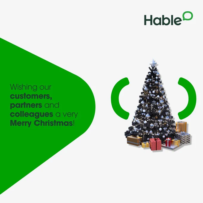 "Wishing our customers, 
partners and colleagues a very Merry Christmas!" written in green next to a photo of a Christmas tree, with lights. And presents under the tree.