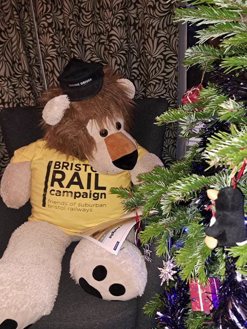 Lilly the Lion, wearing Bristol Rail Campaign t-shirt, reads a railway magazine by the Xmas tree
