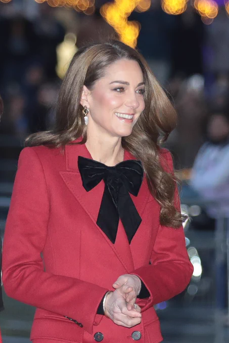 The Princess of Wales, smiling and wearing a red coat, as she arrives outside Westminster Abbey