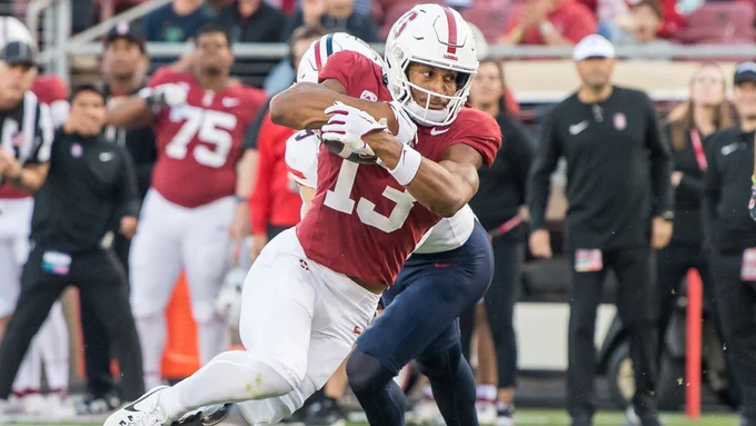 Elic Ayomanor carries the football as a defender tries to tackle him during a Stanford Cardinal football game.