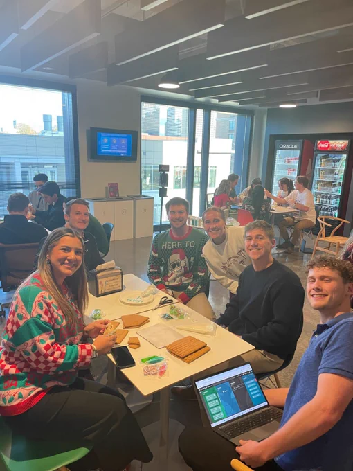 Oracle employees seated at a table wearing ugly holiday sweaters