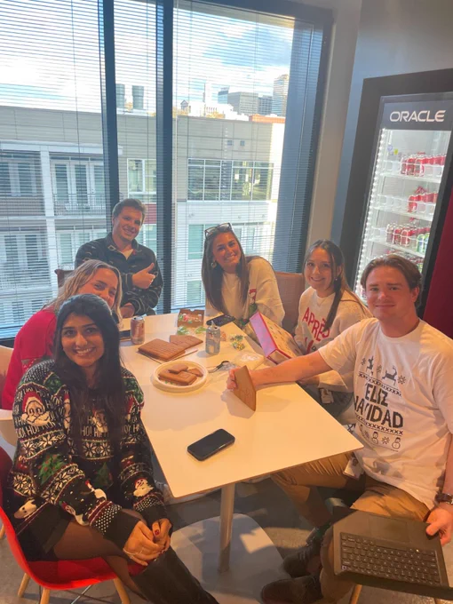 Oracle employees seated at a table wearing ugly holiday sweaters