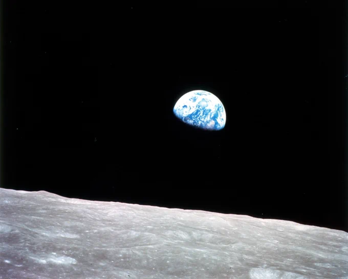 The Earthrise photo taken by Apollo 8 astronaut Bill Anders on December 24, 1968, shows the Moon's surface in the foreground with the Earth appearing above the horizon in the distance in the blackness of space. About 2/3 of the Earth is lit from by the Sun and you can see the ocean, clouds, and a continent on the lit portion.