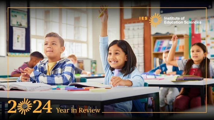 Students raise their hand while sitting at their desks