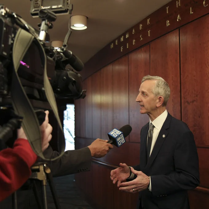 Mayor Wilson stands in front of a television crew, who are interviewing him.