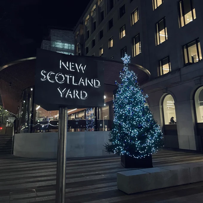 A Christmas tree outside New Scotland Yard with lights on. 