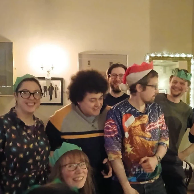 Edinburgh board game shop Ancient Robot Games staff members at a Christmas dinner. Some are smiling and some are looking away.