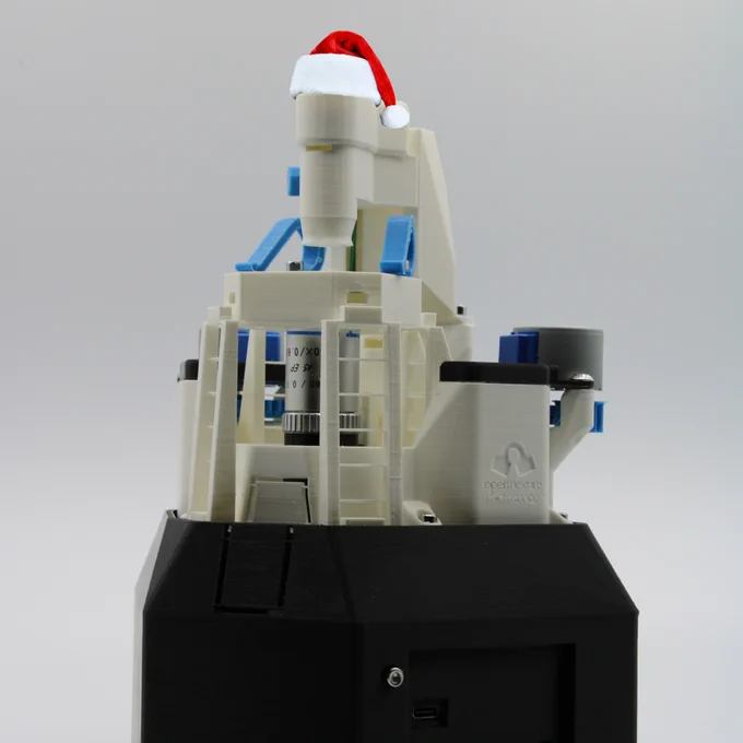 An OpenFlexure Microscope wearing a Santa hat.
