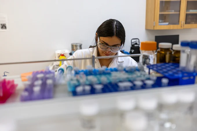 A photo of a person in protective gear working in a lab.