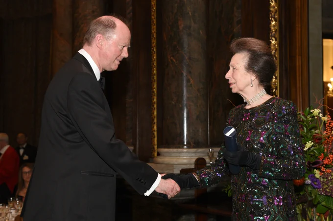 HRH The Princess Royal stood on stage shaking hands with Sir Chris Whitty.
