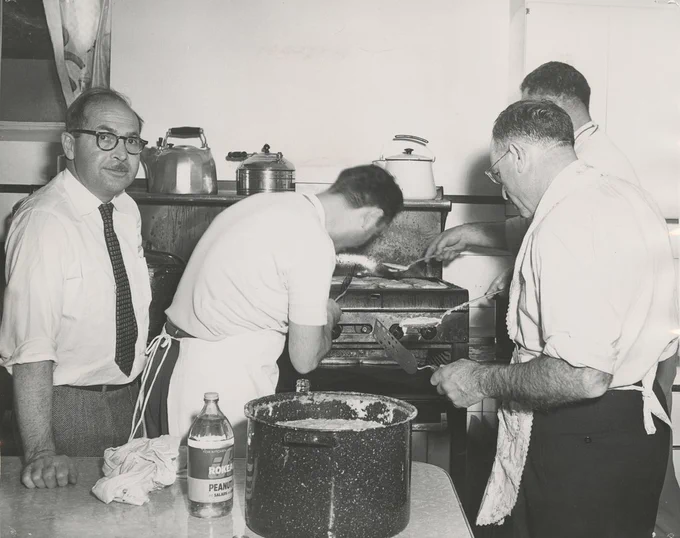 Four men stand around a stove, making latkes
