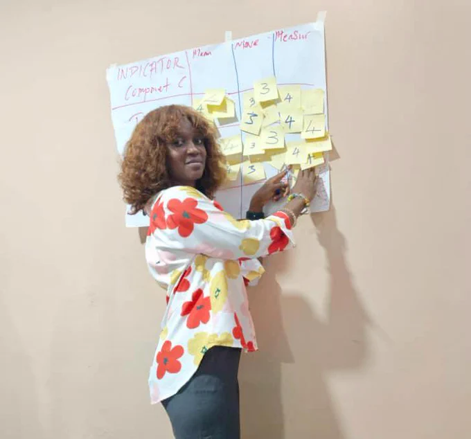 A participant (Fatmata) getting stuck into the 3M prioritization exercise, using post-it notes to classify which project indicators are Meaningful, Moveable, and Measurable.