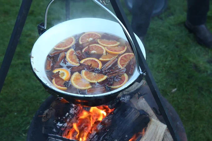 A pot of mulled cider simmering over an open fire.