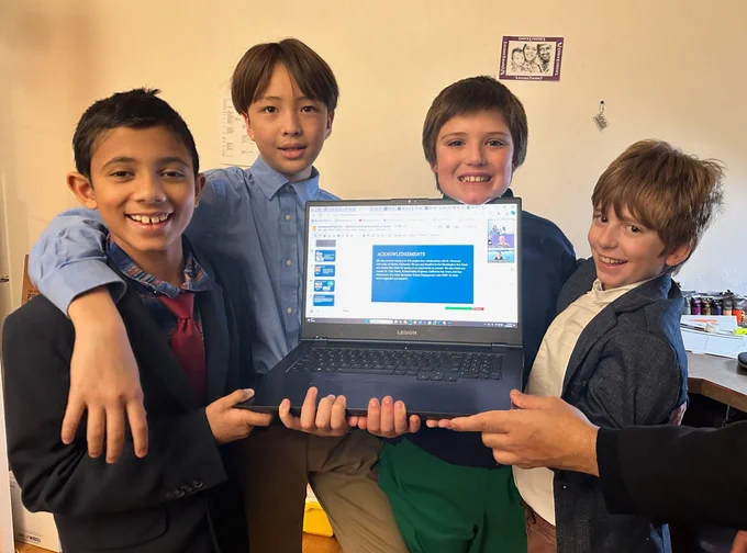 Lewis & Clark Elementary students Nirbhuy, Aisuke, Tristan and Henry pose with a laptop displaying their kelp farming toolkit.