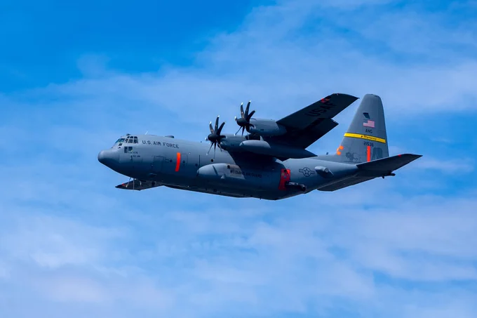 C-130 aircraft flies through the blue sky.
