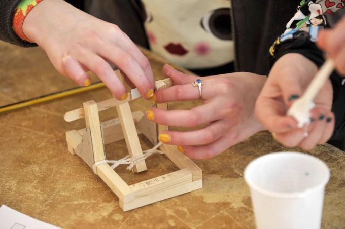 A pair of hands building a catapult