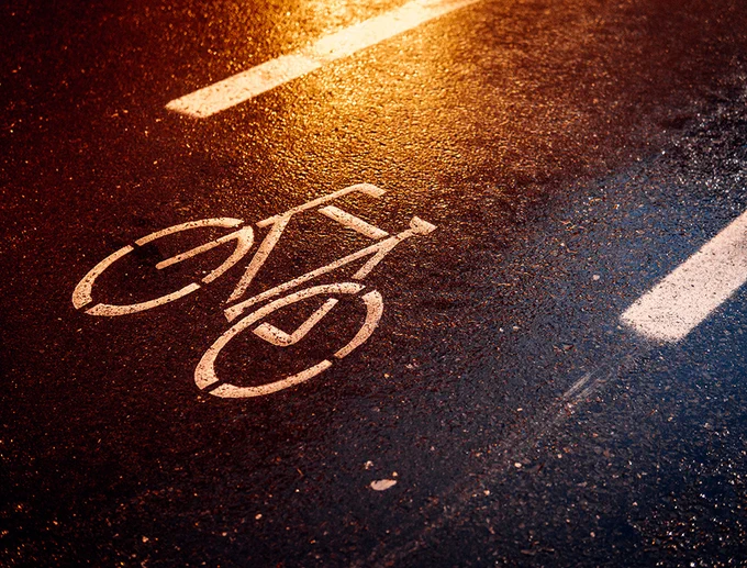 Nasser Fahrradweg in der Dunkelheit mit Lichtreflektionen. Foto: Adobe Stock, ohenze.