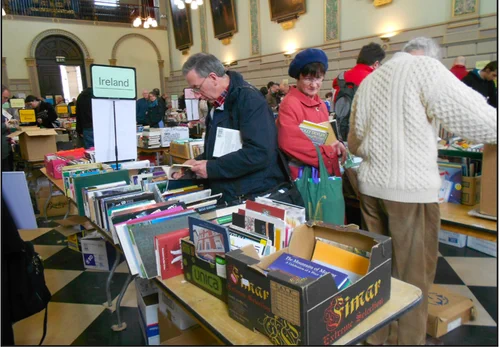 Boxes of books and people looking at books in the Exam Hall at Trinity College Dublin. 