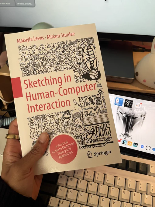 Makayla excitedly holding book in front of their work desk