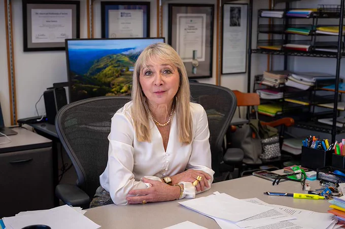 Irene Fonseca sits at her desk and smiles at the camera.