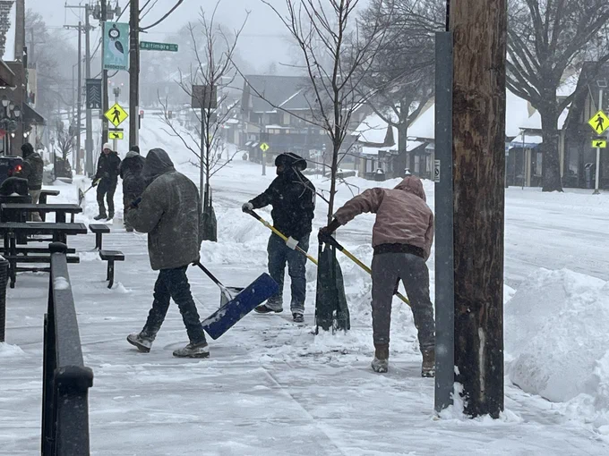 Residents shoveling snow off a sidewalk.