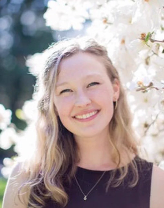Headshot of Anna Duncan with a bright background of white flowers