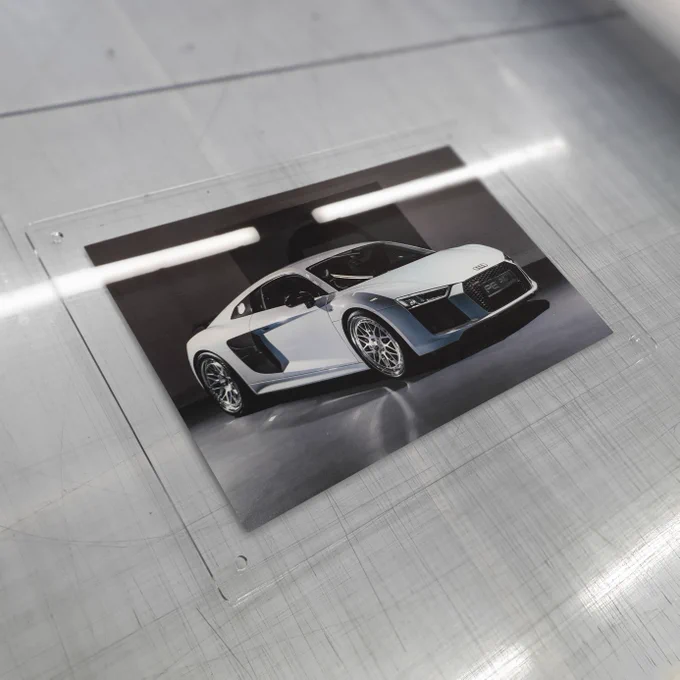Photo of a white Audi R8 featuring silver alloy wheels mounted on a clear acrylic panel. 