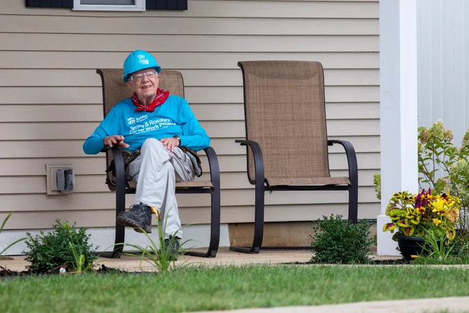 An image of President Jimmy Carter sitting on the porch of a Habitat for Humanity home adjacent to the build site at the 2018 Carter Work Project in St. Joseph County, Indiana.